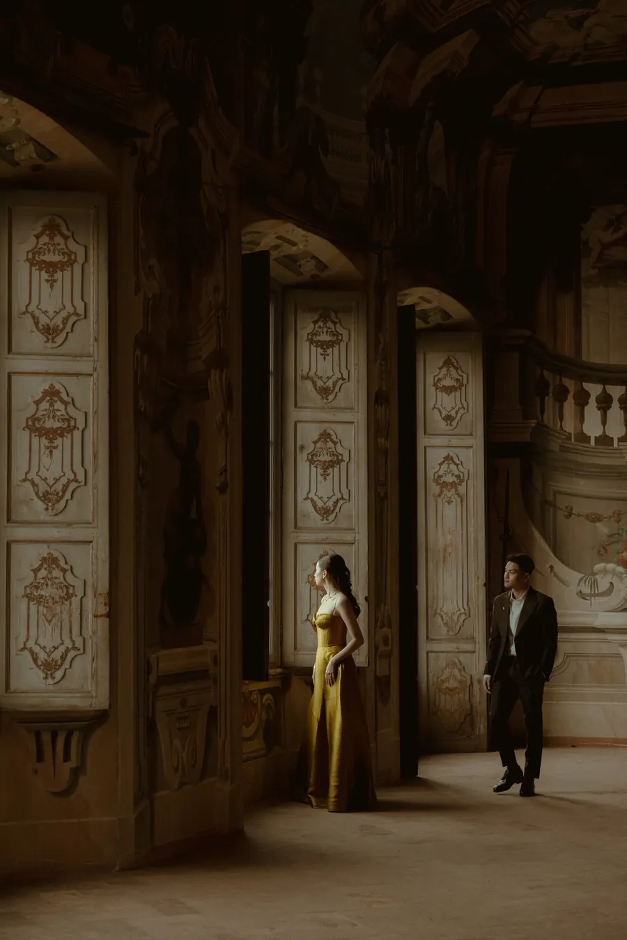 Karin and Matthew standing apart in a frescoed villa hall